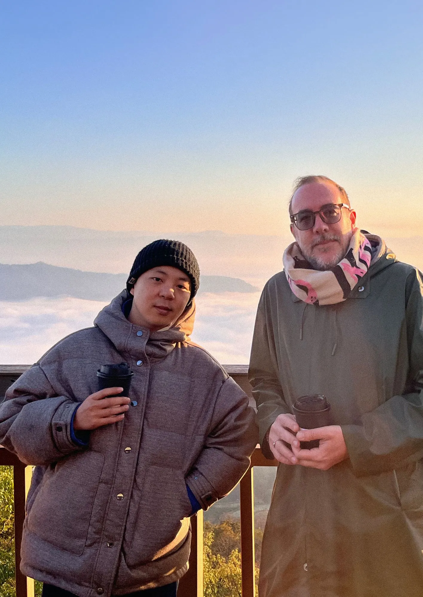 Jixuan and Antoine, founders of Yunma, at daybreak on a Yunnan ridge above a sea of clouds, coffee in hand