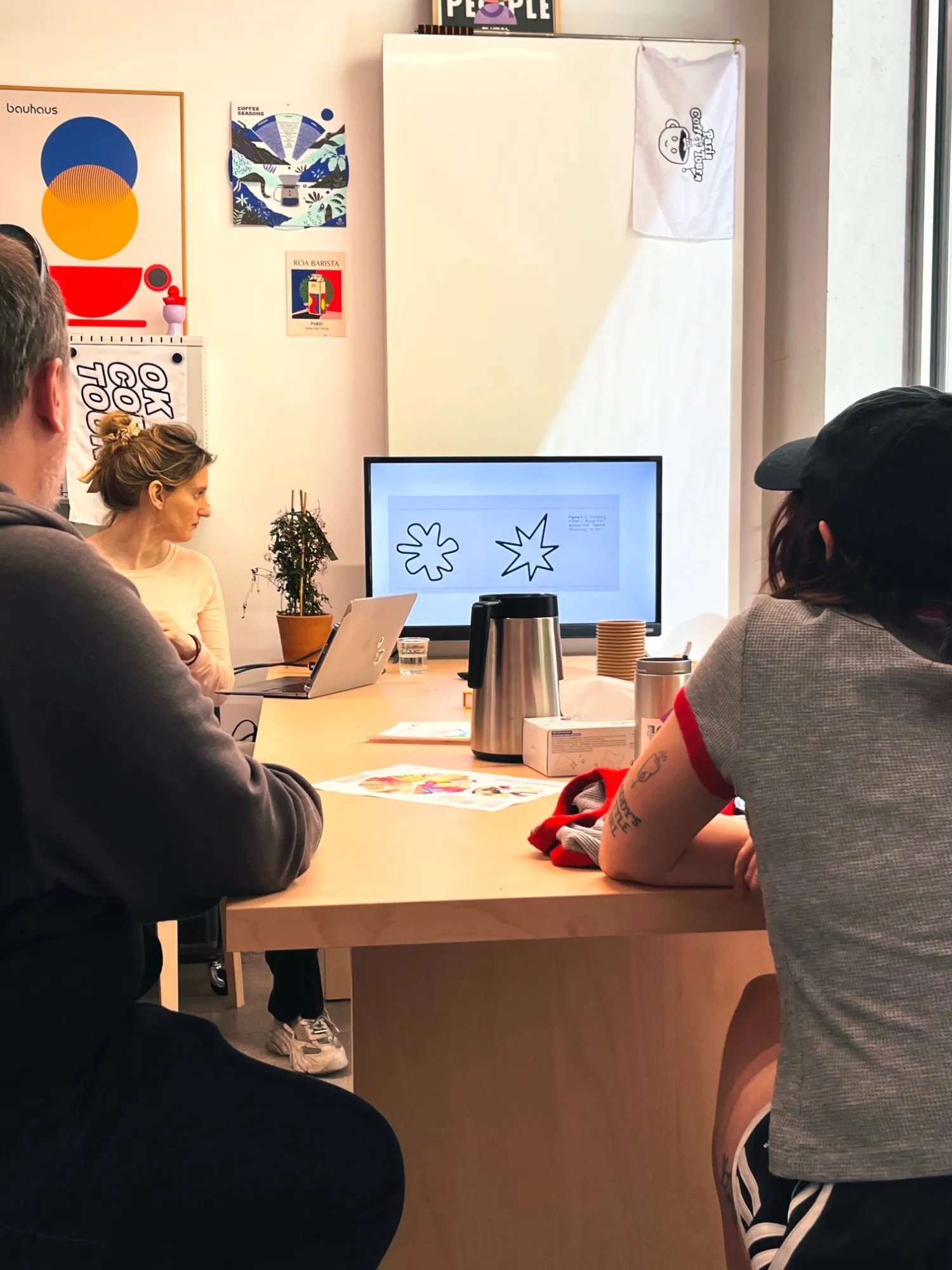 Une assistance assise devant un écran où s’affichent deux formes, l’une arrondie, l’autre pointue, pendant une présentation sur la perception du café