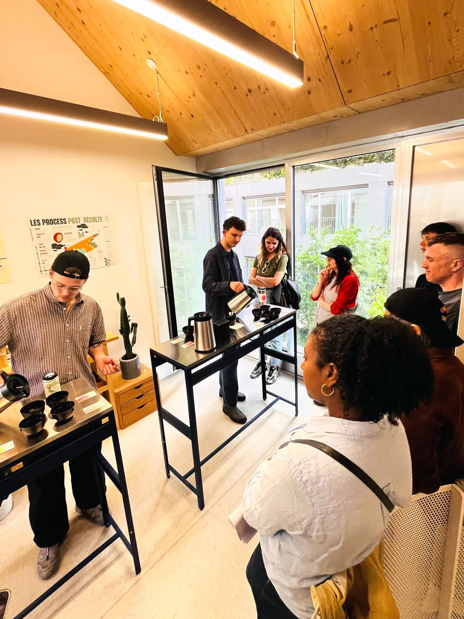 Atelier de dégustation : autour de deux tables hautes, des participants observent pendant qu’un animateur verse l’eau d’une bouilloire sur des bols de dégustation